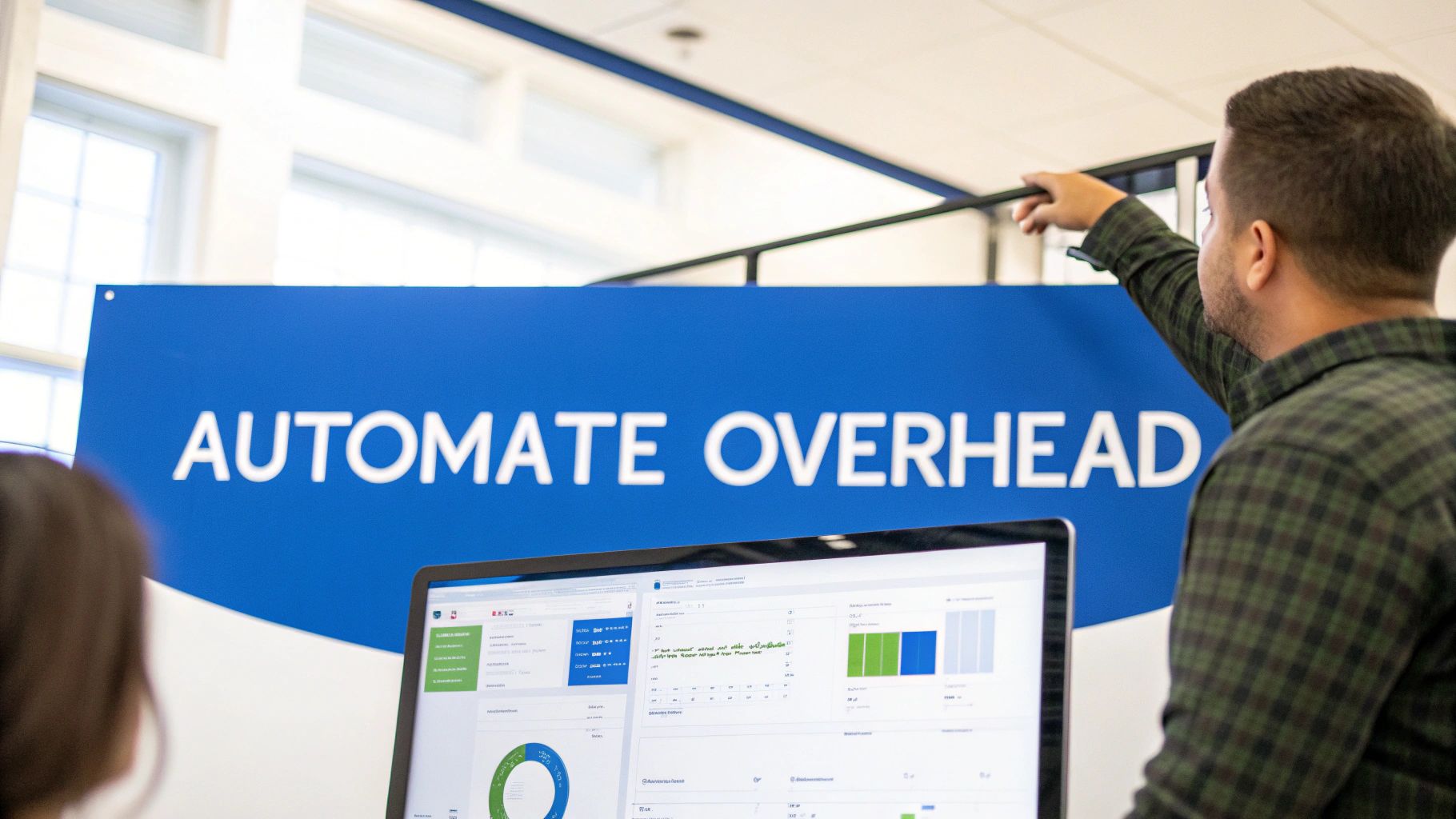 A person points at a blue sign that reads 'AUTOMATE OVERHEAD' while looking at a laptop with business data.