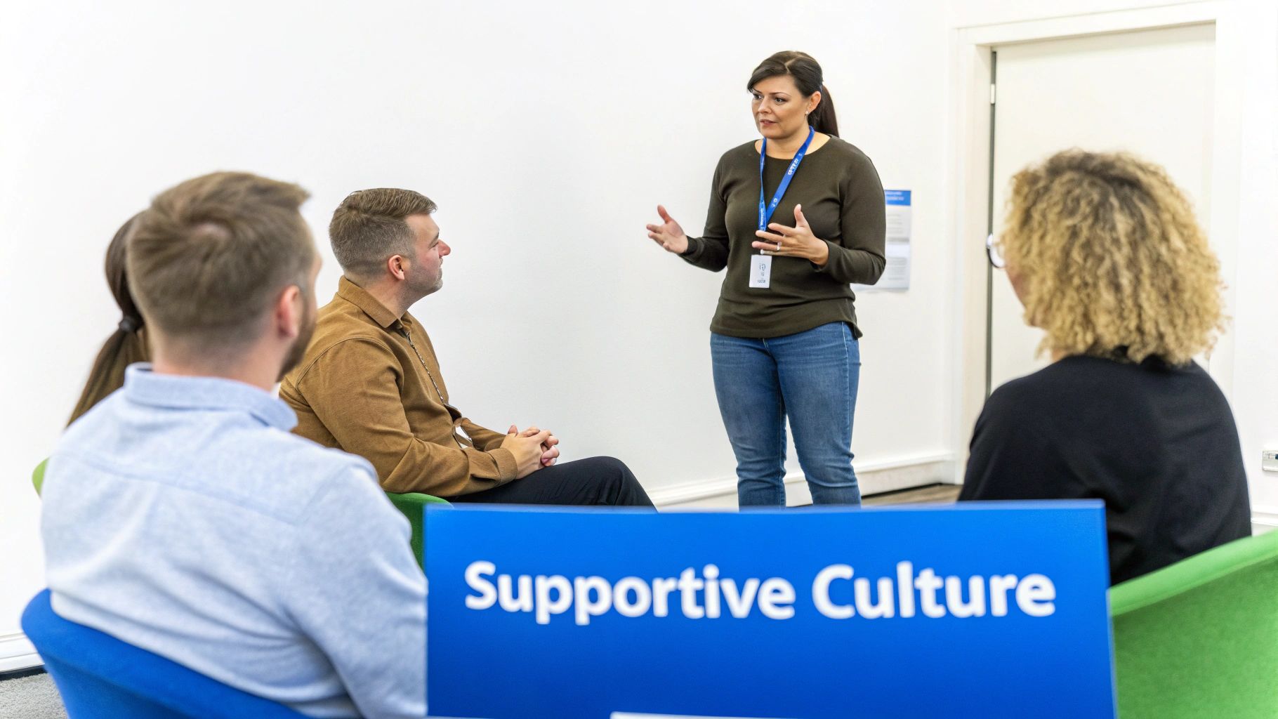 A woman leads a discussion with three other people in a bright room, focusing on a supportive culture.